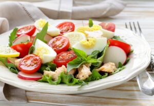 Salat mit Rucola, Tomaten, Lachsforelle, Ei und Radieschen