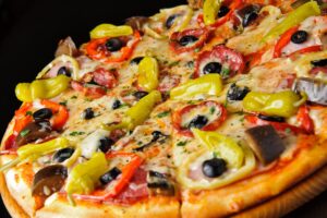 Pizza mit Paprika, Peperoni, Oliven und Salami